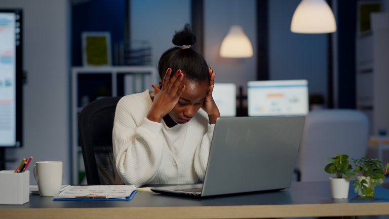 Stressed african businesswoman suffering from headache at work